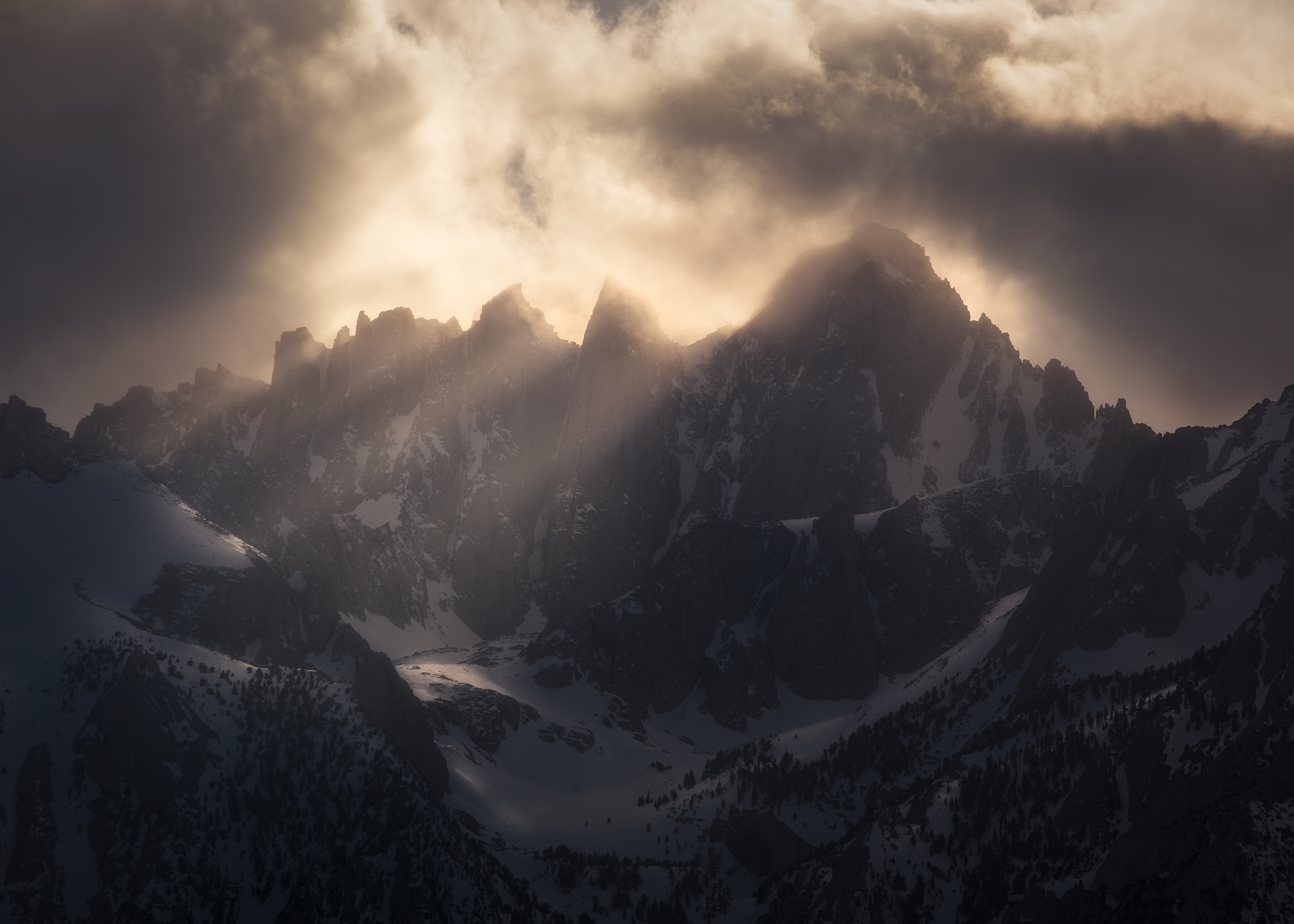 Illuminated mountain peaks emerging through dramatic clouds, photographed by Forrest Stanley